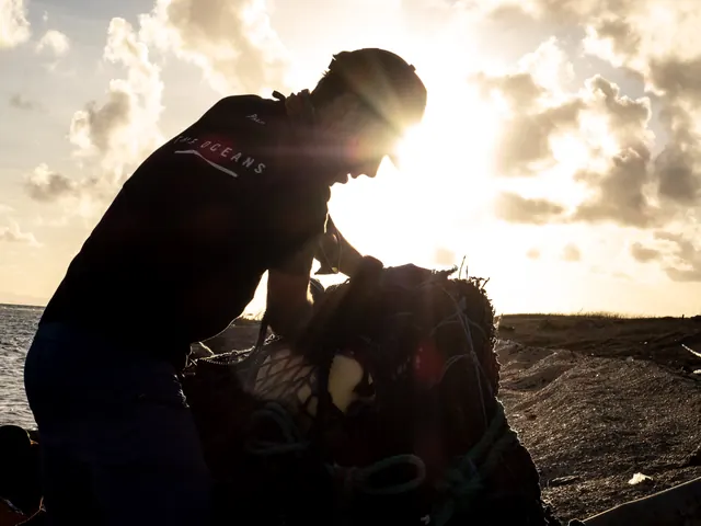 A volunteer hauling a bag of beach plastic, backlit by the sun