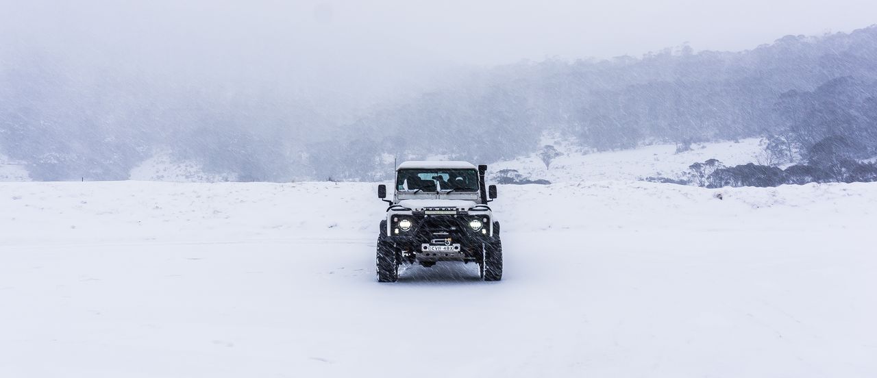 A Land Rover Defender driving through a snowstorm