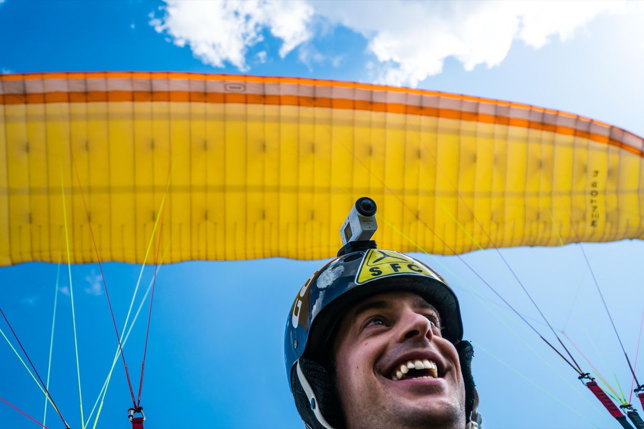 Luke Bakhuizen grinning under a yellow paraglider wing