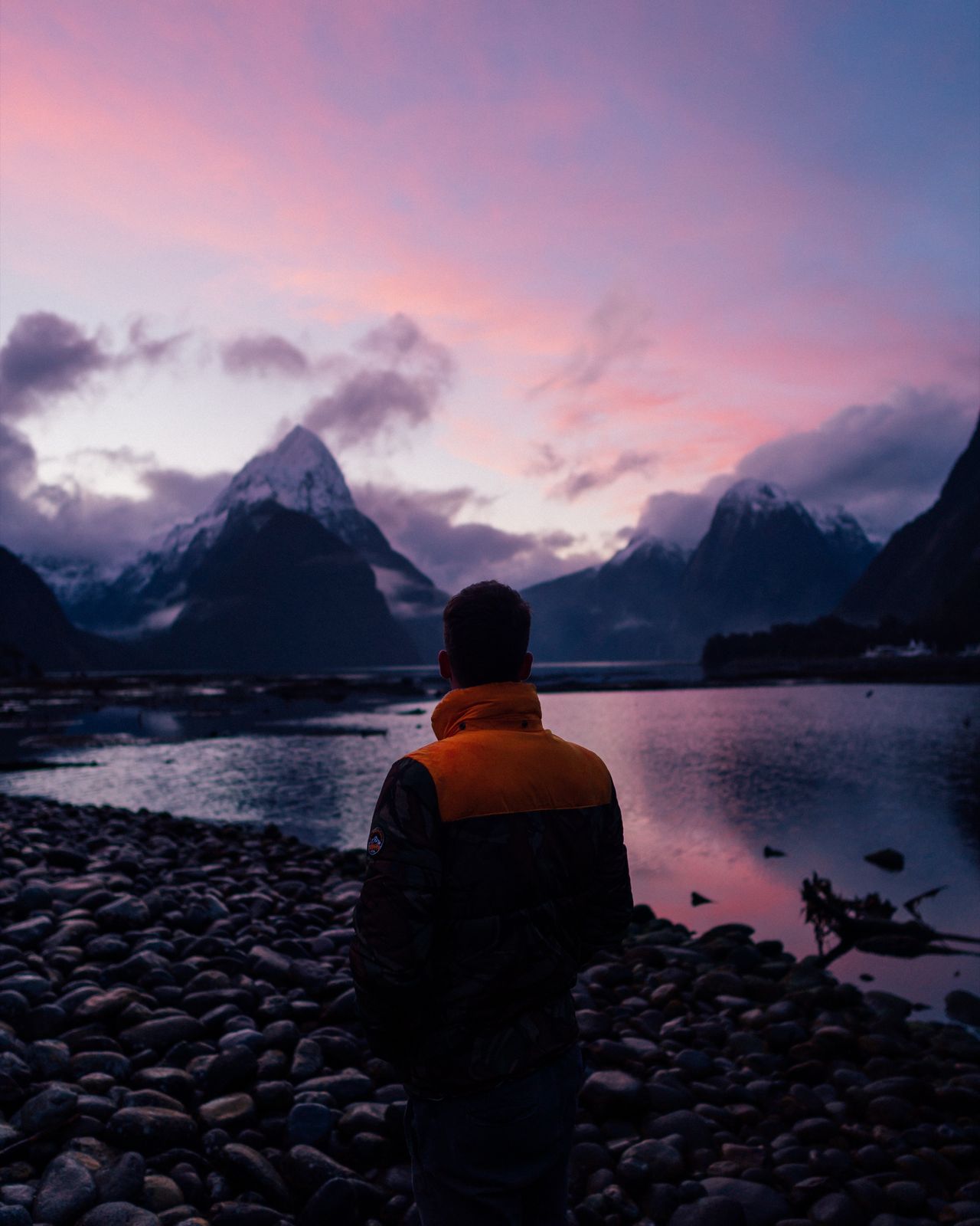 A lone figure facing Mitre Peak under a pink sky