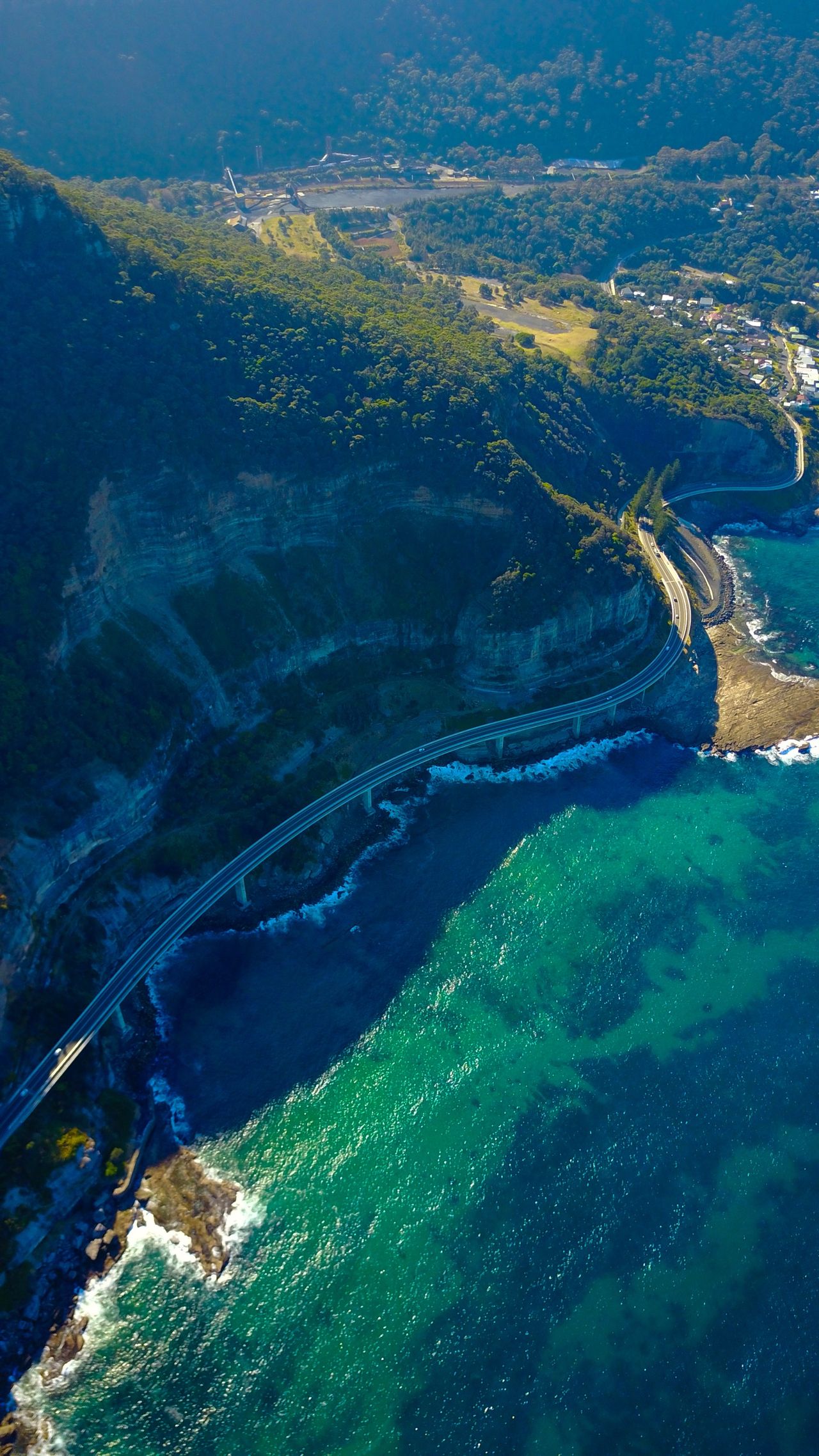 A coastal road cut along sea cliffs, from high above