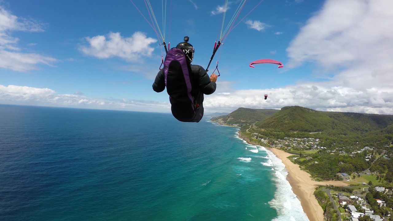 Paragliding along the coast south of Sydney, filmed by chase camera